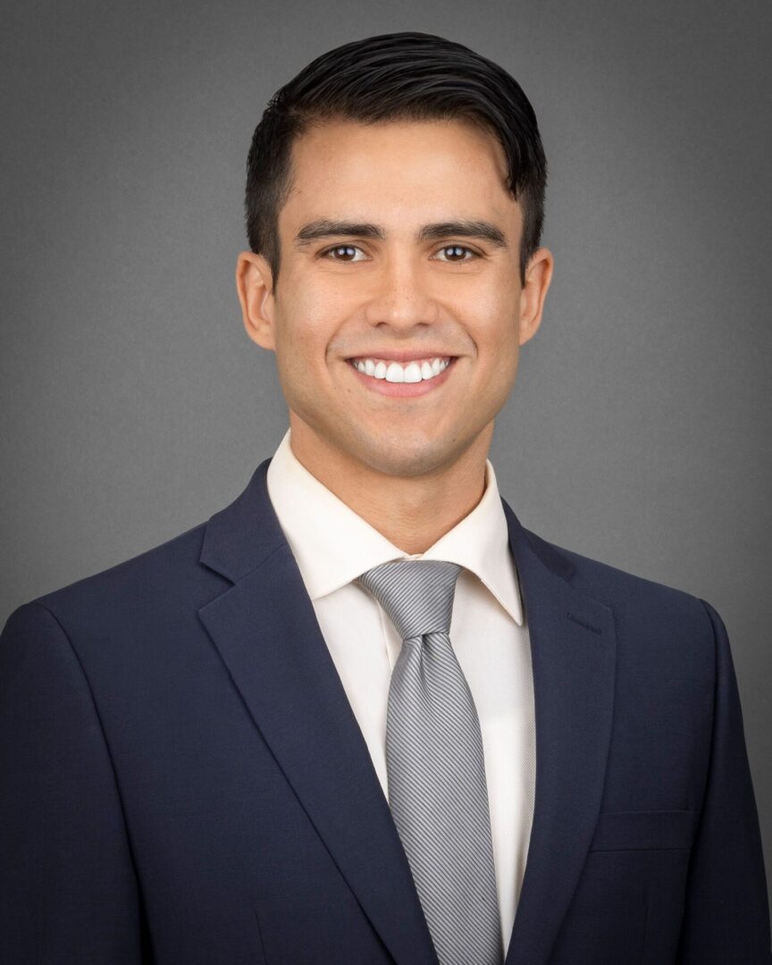 A man in a suit and tie smiling for the camera.